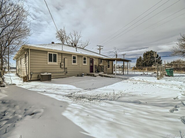 snow covered rear of property featuring cooling unit