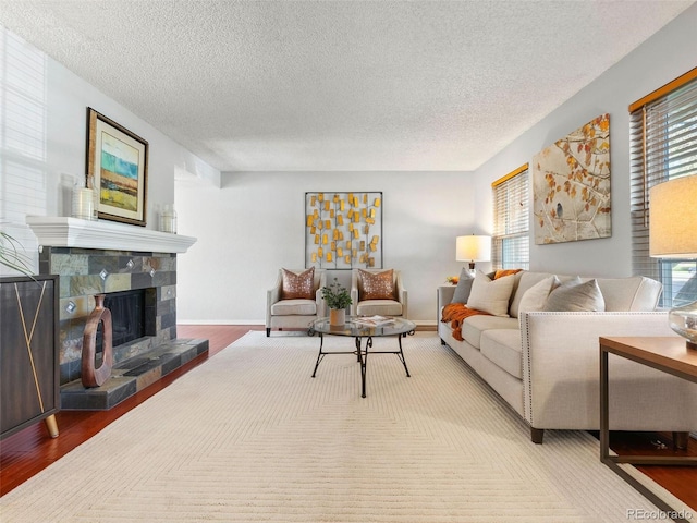 living room featuring a stone fireplace, a textured ceiling, and wood-type flooring