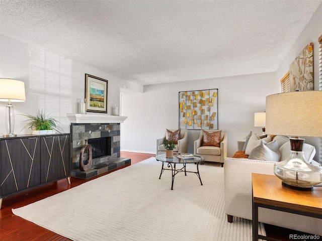 living room with hardwood / wood-style flooring, a textured ceiling, and a tile fireplace