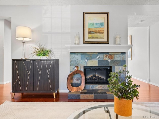 living area featuring a textured ceiling, a stone fireplace, and hardwood / wood-style flooring