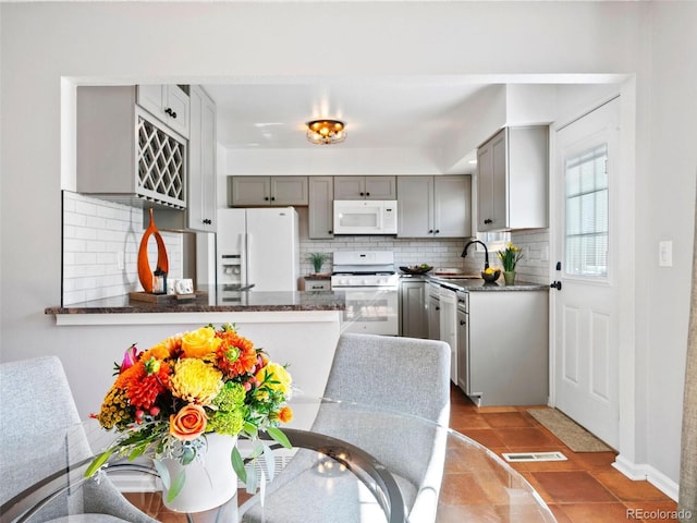 kitchen featuring backsplash, sink, tile patterned floors, white appliances, and gray cabinetry