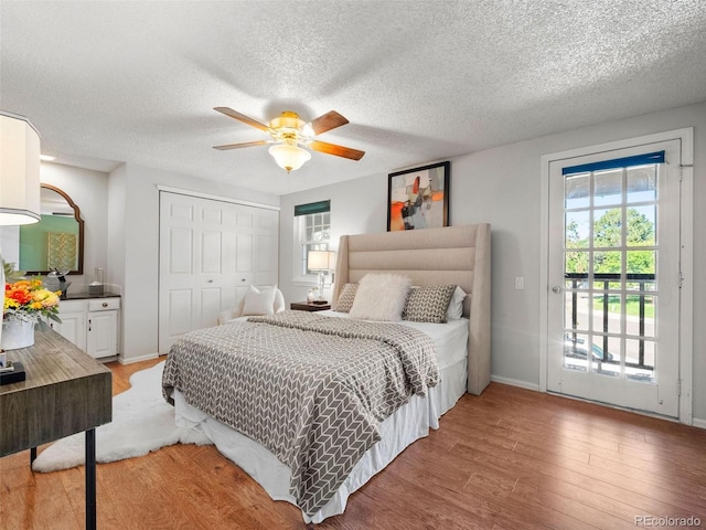 bedroom featuring ceiling fan, a closet, access to exterior, hardwood / wood-style flooring, and a textured ceiling