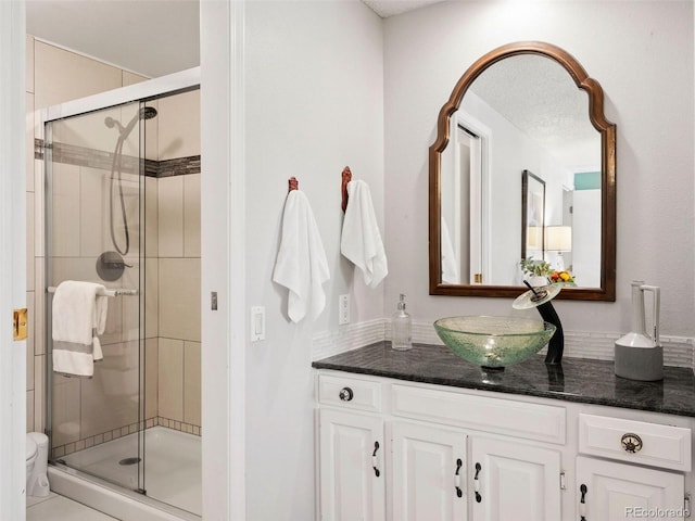 bathroom with a shower with door, vanity, and toilet