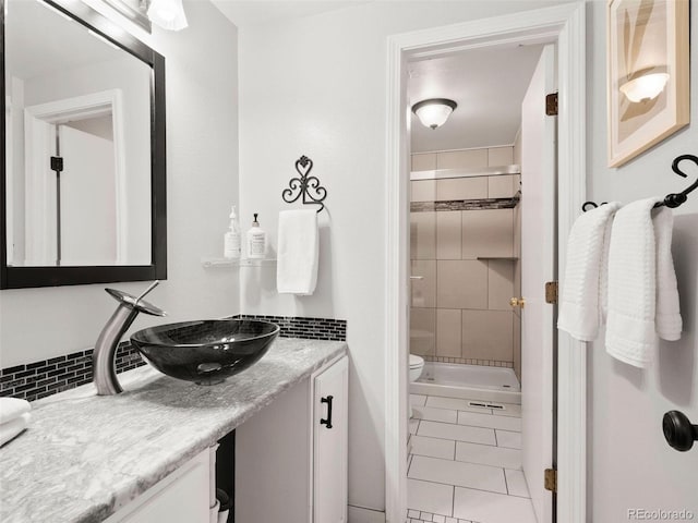 bathroom with tile patterned floors, toilet, a tile shower, and vanity