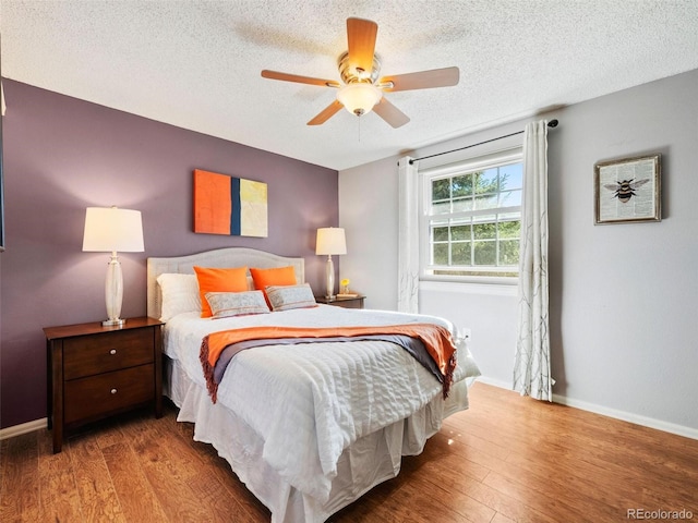 bedroom with a textured ceiling, ceiling fan, and hardwood / wood-style floors