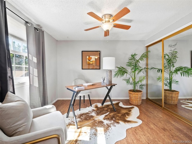 living area featuring a textured ceiling, ceiling fan, and wood-type flooring