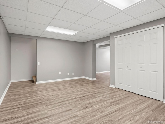 basement with a drop ceiling and light hardwood / wood-style flooring