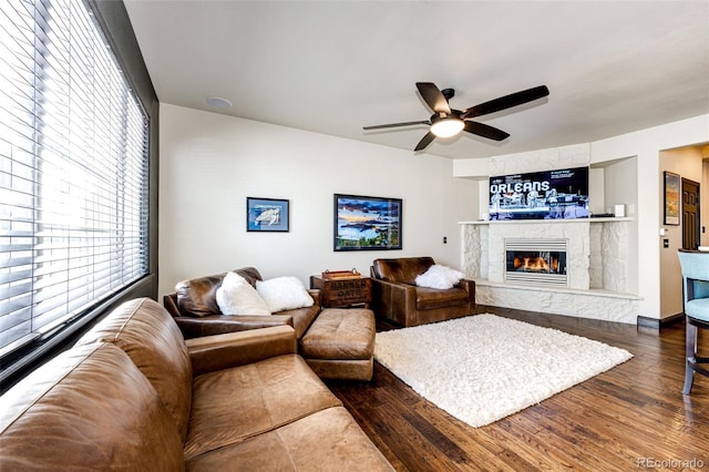 living room with dark hardwood / wood-style floors, ceiling fan, and a premium fireplace