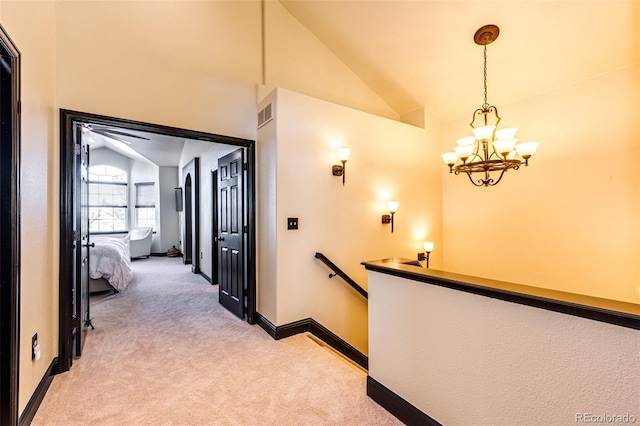 hallway with light carpet, an inviting chandelier, and lofted ceiling