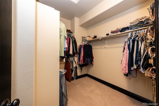 walk in closet with light carpet