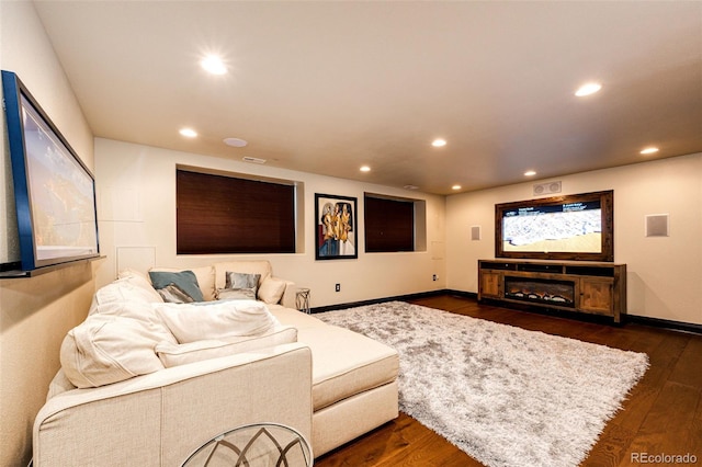 home theater room with dark wood-type flooring and a fireplace