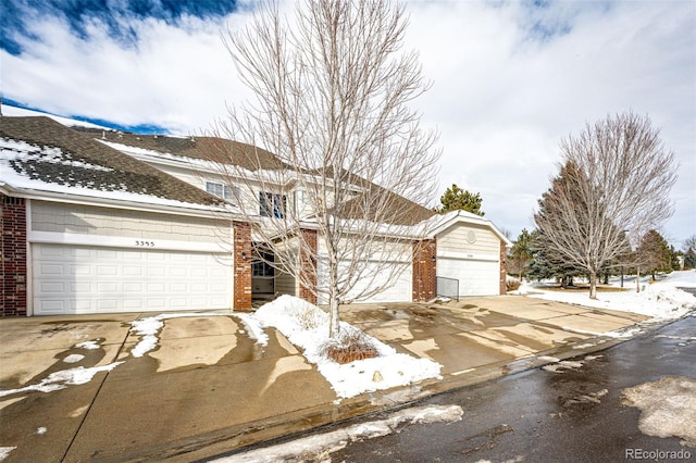 traditional home featuring a garage, concrete driveway, and brick siding