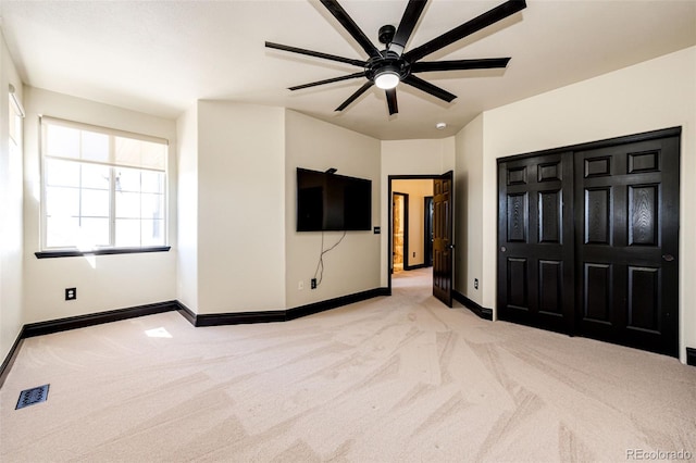 unfurnished bedroom with carpet flooring, baseboards, a ceiling fan, and a closet