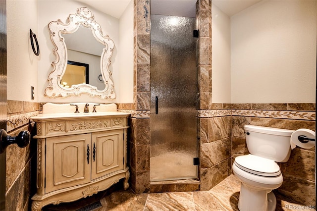 full bath with tile walls, a stall shower, wainscoting, vanity, and toilet
