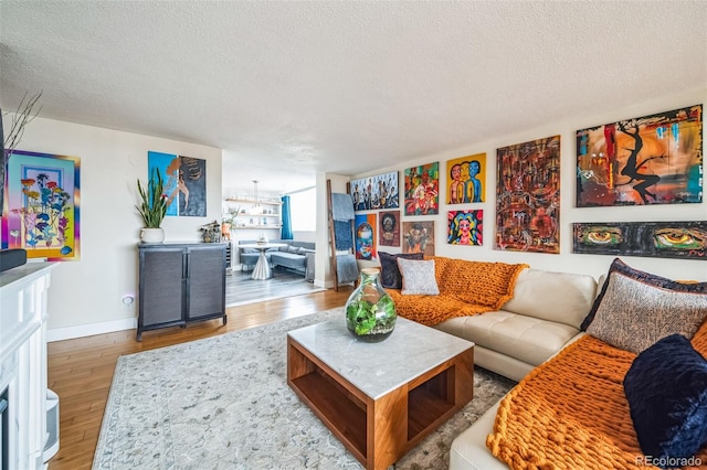 living area with wood finished floors, baseboards, and a textured ceiling