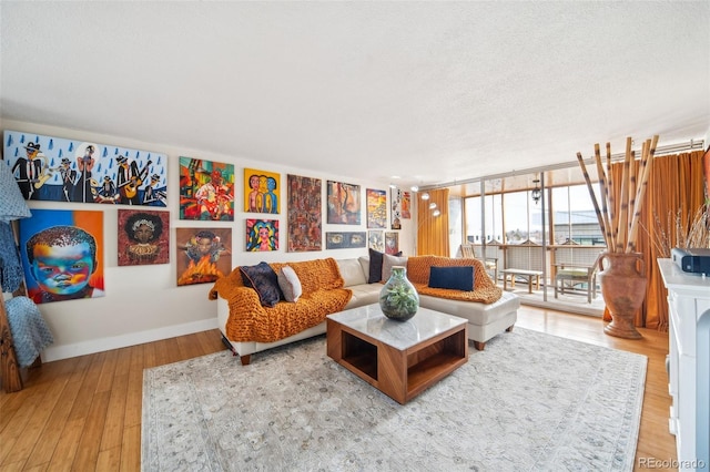 living area with a textured ceiling, wood finished floors, baseboards, and expansive windows