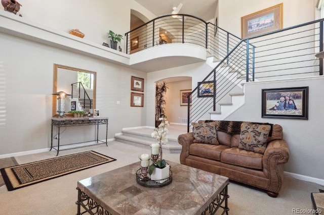 9531 Desert Willow Way, Highlands Ranch, CO 80129 - living area featuring arched walkways, a high ceiling, stairs, carpet flooring, and baseboards