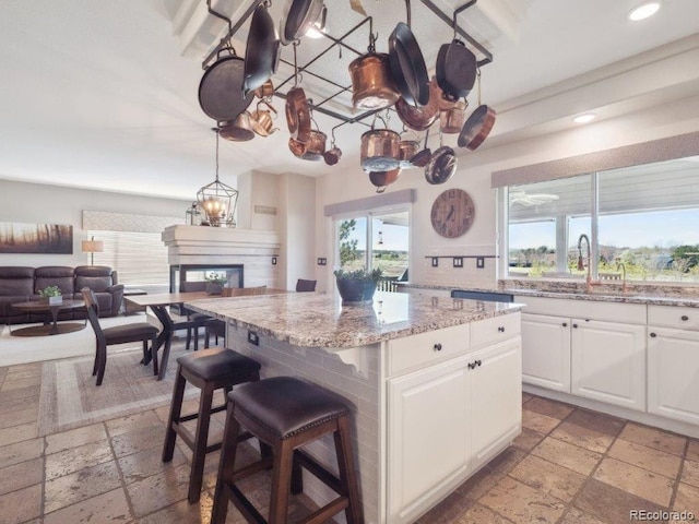 9531 Desert Willow Way, Highlands Ranch, CO 80129 - kitchen featuring stone tile floors, a multi sided fireplace, recessed lighting, white cabinetry, and a kitchen island