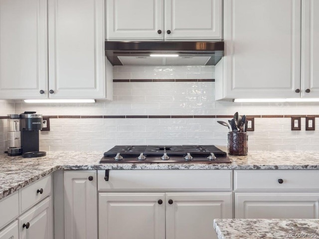 9531 Desert Willow Way, Highlands Ranch, CO 80129 - kitchen featuring under cabinet range hood, white cabinets, decorative backsplash, and stainless steel gas stovetop