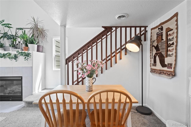 970 S Dawson Way Unit 9, Aurora, CO 80012 - dining space with carpet flooring, a textured ceiling, stairway, and a tile fireplace