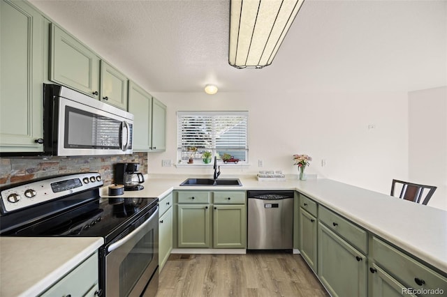 11100 Callaway Ct, Parker, CO 80138 - kitchen with appliances with stainless steel finishes, green cabinetry, light wood-style flooring, decorative backsplash, and light countertops