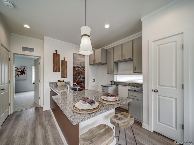 kitchen featuring a breakfast bar, sink, kitchen peninsula, pendant lighting, and hardwood / wood-style floors