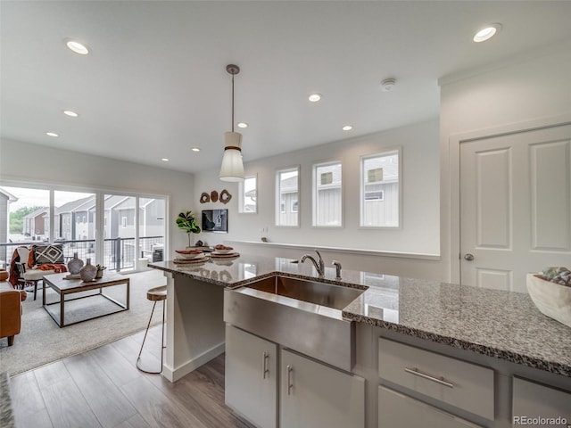 kitchen featuring light stone counters, a wealth of natural light, hanging light fixtures, and white cabinets