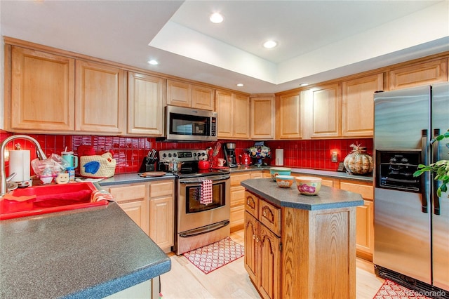 kitchen with a center island, a raised ceiling, sink, light hardwood / wood-style floors, and stainless steel appliances