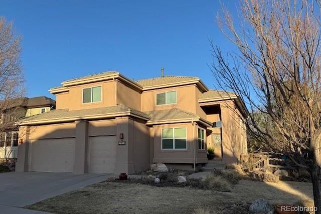 view of front facade with stucco siding, a garage, and concrete driveway