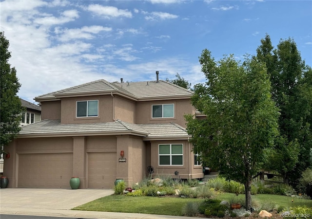 prairie-style home featuring a tile roof, a front yard, stucco siding, a garage, and driveway