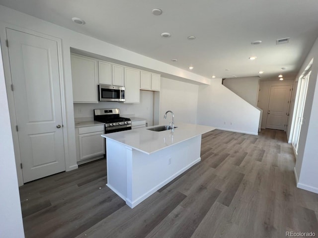 6658 N Nepal Ct, Aurora, CO 80019 - kitchen featuring stainless steel appliances, a sink, wood finished floors, white cabinets, and an island with sink