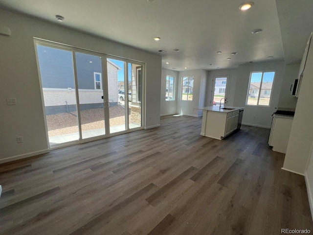 6658 N Nepal Ct, Aurora, CO 80019 - unfurnished living room with a sink, plenty of natural light, recessed lighting, dark wood-type flooring, and baseboards