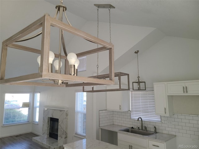 kitchen with backsplash, white cabinetry, sink, and a high end fireplace