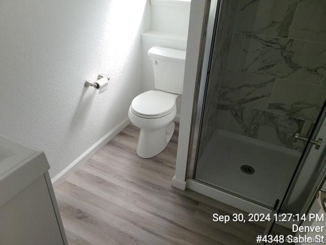 bathroom featuring wood-type flooring, vanity, toilet, and a shower with shower door