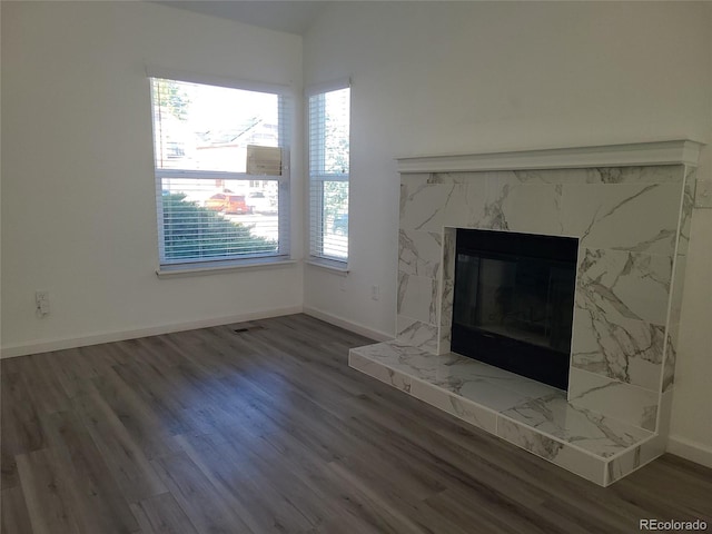 unfurnished living room featuring lofted ceiling, a high end fireplace, and dark wood-type flooring