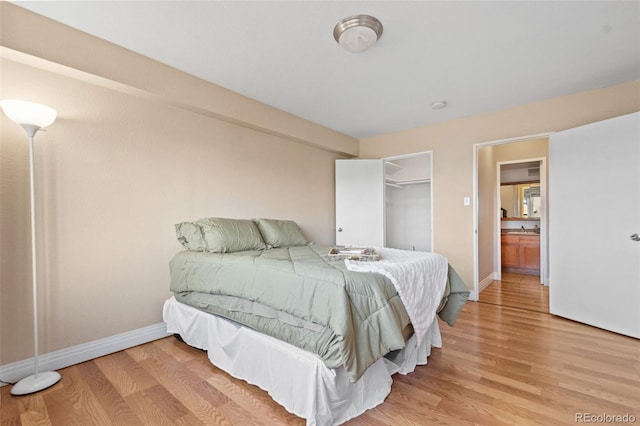 bedroom with a walk in closet, a closet, and light hardwood / wood-style floors