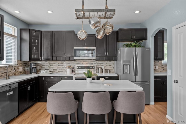 13322 Meadow Park Ln, Broomfield, CO 80020 - kitchen featuring stainless steel appliances, backsplash, a breakfast bar area, light countertops, and glass insert cabinets