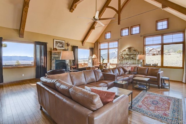 living area with high vaulted ceiling, hardwood / wood-style floors, a ceiling fan, baseboards, and beamed ceiling