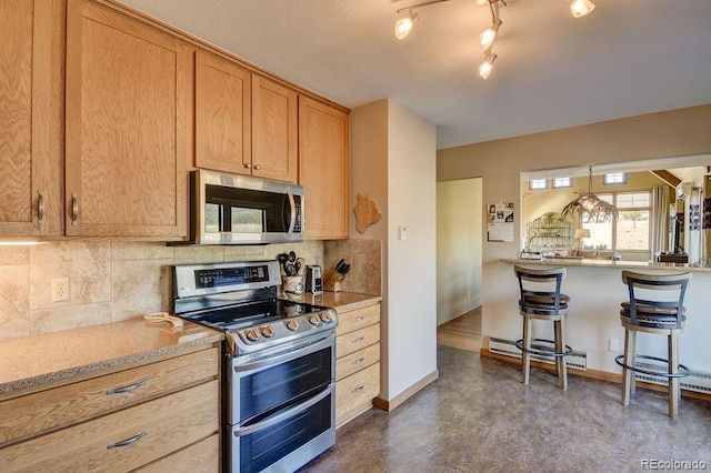 kitchen featuring stainless steel appliances, baseboards, finished concrete floors, backsplash, and a baseboard heating unit