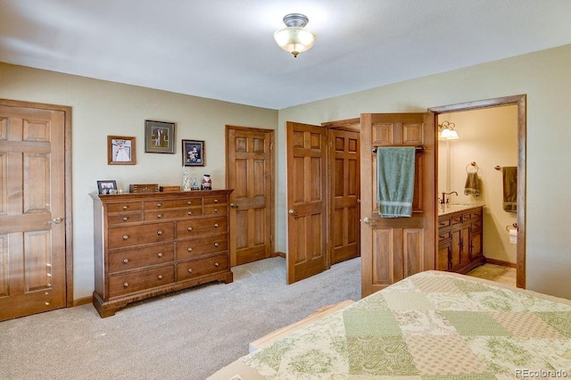 bedroom with light colored carpet, connected bathroom, baseboards, and a sink