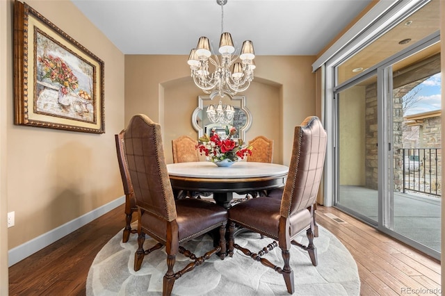 dining area featuring dark wood-type flooring and a notable chandelier