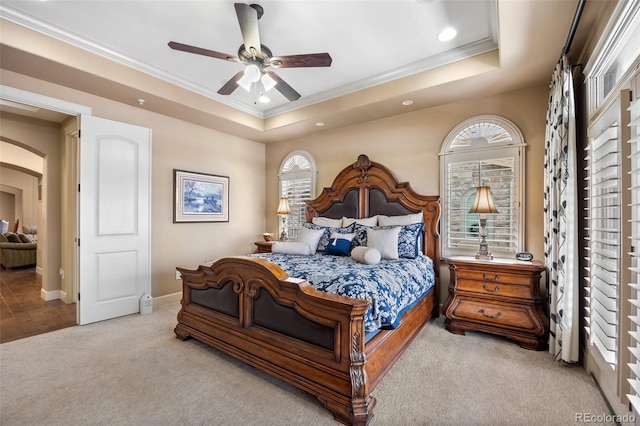 bedroom featuring a raised ceiling, ceiling fan, light carpet, and crown molding