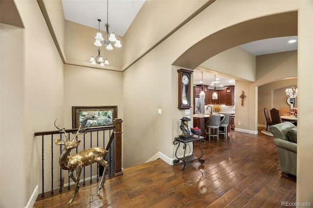 entryway featuring a chandelier, arched walkways, high vaulted ceiling, and dark wood-type flooring