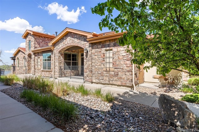 view of front of home featuring stone siding, fence, and stucco siding
