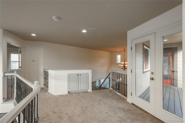 carpeted spare room with french doors and a notable chandelier