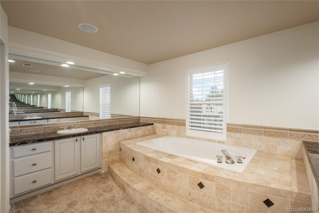 bathroom with vanity and tiled bath