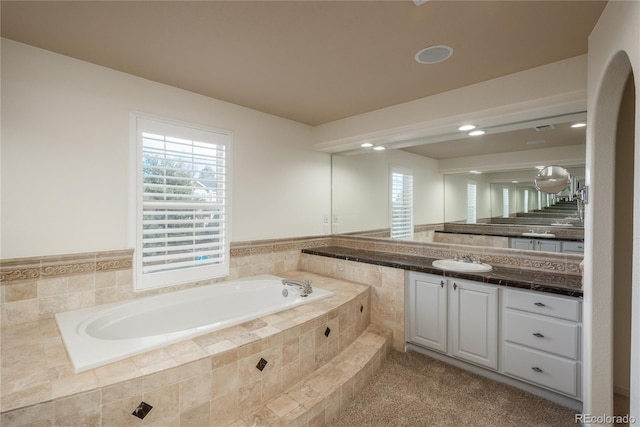 bathroom with vanity and a relaxing tiled tub