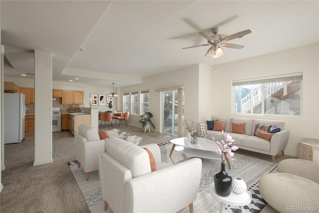 living room featuring ceiling fan with notable chandelier, light colored carpet, plenty of natural light, and sink