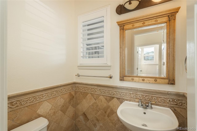 bathroom featuring sink, tile walls, and toilet