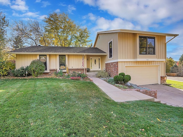 tri-level home featuring driveway, a front lawn, and brick siding